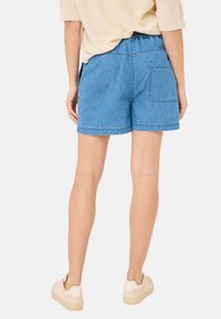 Szorty dżinsowe z elastycznym pasem, jasnoniebieski kolor, gładka tekstura i jedna tylna kieszeń. Widoczne płaskie przeszycia.
