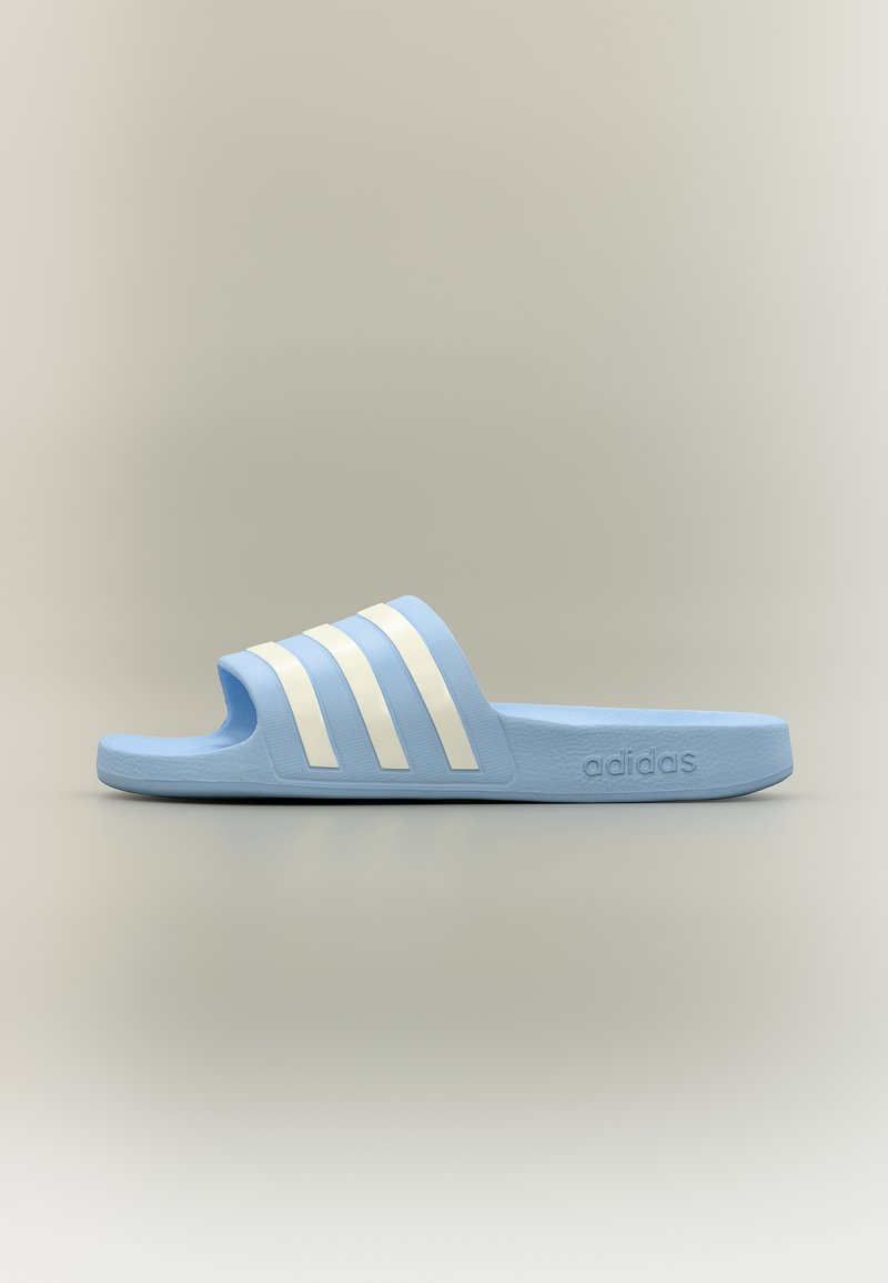 Sandale slide Adidas bleu clair avec trois bandes blanches sur la bride et le logo Adidas sur le côté, vue de profil.