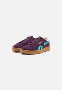 Zapatillas de ante moradas con acentos en verde azulado y una pestaña en el talón blanca. Con suela de goma y puntera perforada para mayor transpirabilidad.