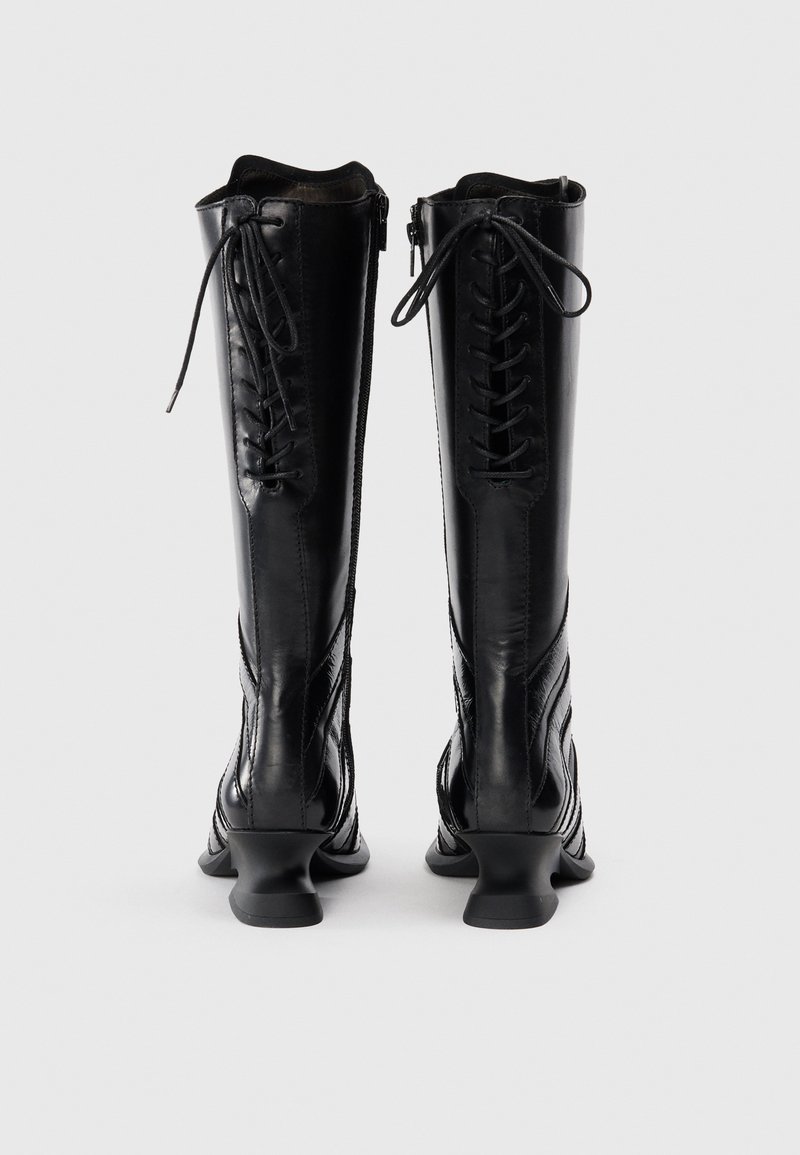 Schwarze kniehohe Stiefel aus glänzendem Leder, mit Schnürung vorne und Reißverschluss. Gebogener Absatz und strukturierte seitliche Details.