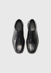 Zapatos de vestir de cuero negro con una textura lisa, punta redondeada y diseño de cordones. Presentan costuras sutiles y una suela baja de goma.