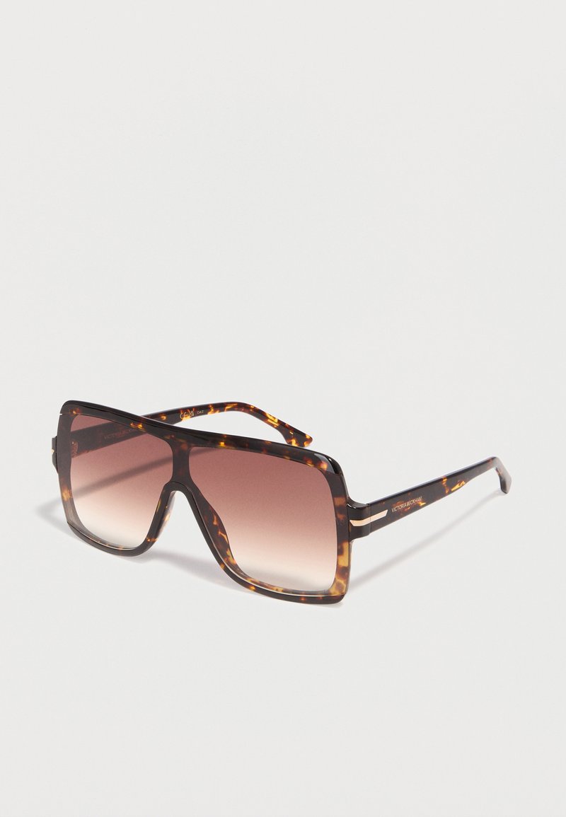 Πολύ μεγάλα τετράγωνα γυαλιά ηλίου με σκελετό από χελώνα και καφέ φακούς με διαβάθμιση, τοποθετημένα με κλίση σε λευκή επιφάνεια.