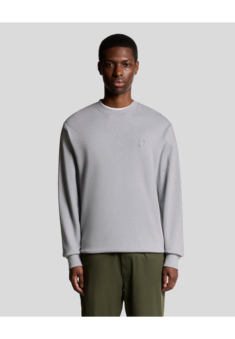 Grå sweatshirt gjord av mjukt material med rundad hals och långa ärmar, som har en liten broderad logotyp på bröstet.
