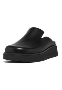 Black leather slip-on shoe with a low platform, rounded toe, and cut-out design on the upper for breathability. Minimalist style.