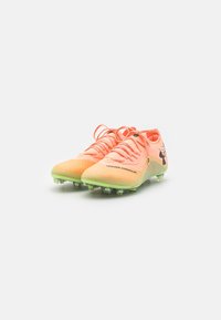 Scarpe da calcio di un brillante arancione e verde con tomaia in mesh testurizzato, dotate di chiusura con lacci e tacchetti in plastica per la trazione.