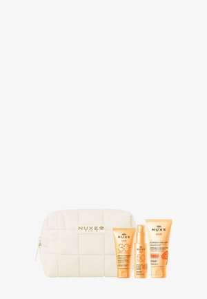 Beige gesteppte Kosmetiktasche mit drei NUXE Sun Hautpflegeprodukten: SPF 30 Creme, SPF 50 Spray und After-Sun-Lotion.