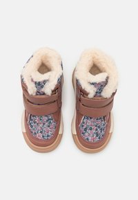 Pruunid talvesaapad lillemustriga kangast, pehme karvase voodriga ja kahe Velcro rihmaga sulgemiseks ja reguleeritavaks sobivuseks.