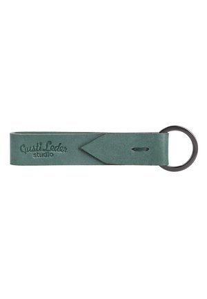 Grüne Leder-Schlüsselanhängerschlaufe mit geprägtem "Gusti Leder studio" Text und einem schwarzen Metall-Schlüsselring befestigt.