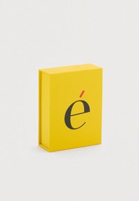 Κίτρινο ορθογώνιο κουτί με μια έντονη μαύρη στυλιζαρισμένη γράμμα "é" με κόκκινο τόνο πάνω. Ομαλή ματ υφή, απλός σχεδιασμός.