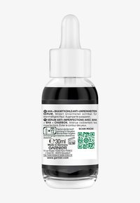 Droppflaska med mörk serum, vit kapsyl, 30 ml etikett, streckkod och flerspråkig text på en genomskinlig bakgrund. Tillverkad i Tyskland.