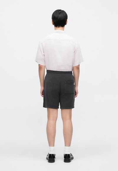 Shorts en coton gris avec une taille élastique et une poche arrière unique, assortis à une chemise à manches courtes rose clair, vus de dos.