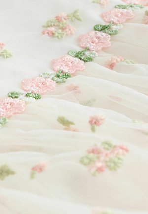 Tissu en tulle blanc orné de broderies florales roses et vertes, présentant des fleurs douces et texturées ainsi que de délicats accents de feuilles.