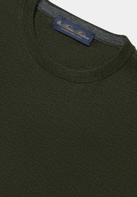 Tmavě zelený pletený svetr s kulatým výstřihem a žebrovanými lemy. Zahrnuje modrou visačku se zlatým nápisem značky.