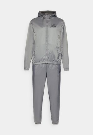 Gray windbreaker suit, featuring a zip closure, hood, elastic cuffs, and pants with ankle cuffs. Made of smooth, shiny fabric with logo detail.