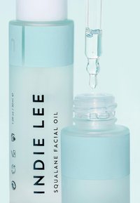 Przezroczysta szklana butelka oleju do twarzy z squalanem z miętowymi akcentami. Posiada zakraplacz i drukowaną etykietę. Gładka tekstura, minimalistyczny design.