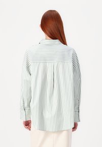 Langermet skjorte i lysegrønn og hvite striper, med bakfold, klassisk krage og knappede mansjetter. Glatt, lett stoff.
