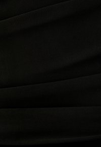 Svart texturerad tyg med ett hexagonalt nätmönster, med subtila veck. Ytan verkar mjuk och lätt.