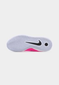 Σόλα ροζ και λευκού παπουτσιού Nike με υφή λευκής πέλματος, μαύρο λογότυπο Nike swoosh και εξαγωνικό σχέδιο κοντά στη φτέρνα.
