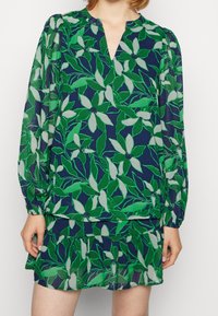 Blouse met lange mouwen en V-hals, bedrukt met een bloemmotief in groen en marineblauw. Lichtgewicht stof met geplooide mouwen en een losse pasvorm.