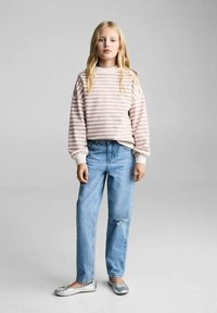 Felpa a righe rosa e bianca, vestibilità rilassata, abbinata a jeans sbiaditi blu chiaro e ballerine argentate metallizzate.