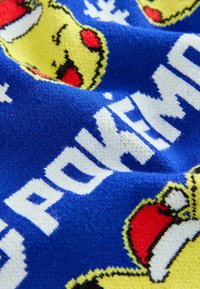 Tissu bleu avec texte blanc indiquant "POKEMON" et visages jaunes de Pikachu portant des bonnets rouges de Noël.