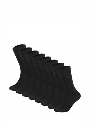 Chaussettes en coton noires disposées en rang, avec un ourlet côtelé et une texture lisse. Chaque chaussette présente une minimaliste sur le côté.