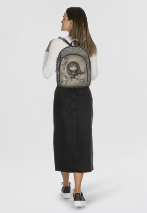 Grauem Rucksack mit transparentem Frontbereich, der ein Cartoon-Mädchen, dekorative Akzente und den Text "Träume" zeigt. Wird auf dem Rücken einer Person getragen.
