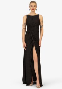 Schwarzes Abendkleid mit taillierter Oberseite, seitlichem Schlitz und verdrehtem Detail an der Taille. Der Stoff hat einen subtilen Schimmer.