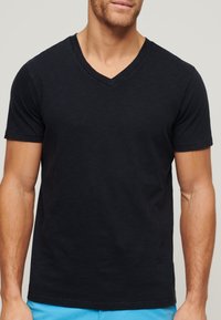 Camiseta negra de manga corta y escote en V, en tejido ligero, con un corte holgado y una textura suave, adecuada para el uso diario.