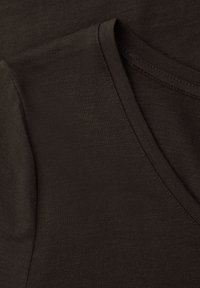 Nærbillede af mørkebrun stof med V-udskæring og korte ærmer på en blød bomuldsskjorte.