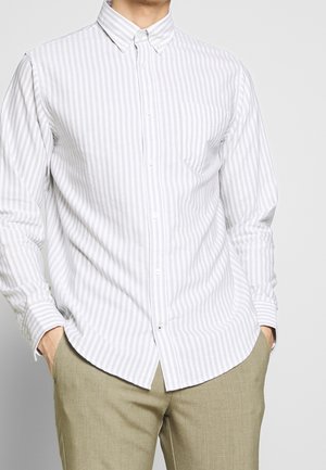 Camicia bianca con bottoni, a righe verticali grigie sottili, con colletto a punta e taschino sul petto, realizzata in un tessuto leggero e liscio.