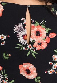 Telaje con estampado floral en negro con grandes flores melocotón y blancas. Presenta un pequeño corte en forma de llave en el escote, asegurado por un botón.