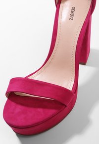 Fuchsia suède sandaal met hoge hak en plateau, met een brede band over de tenen en een blokhak. Zachtleren binnenzool.