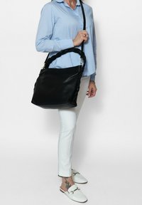 Borsa a spalla in pelle nera con tracolla intrecciata, forma rettangolare, superficie liscia, dotata di hardware in argento e un ampio interno.