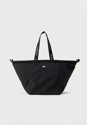 Čierna taška na rameno s širokým horným okrajom, nášivkou s logom na prednej strane a dvoma ramennými popruhmi s bielym nápisom "tommyjeans".