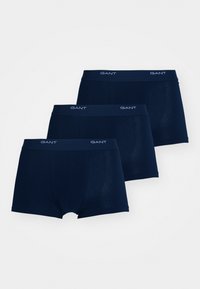 Drei dunkelblaue Herrenboxershorts mit GANT-Logo auf elastischem Bund, arrangiert in einem gestaffelten Stapel auf weißem Hintergrund.