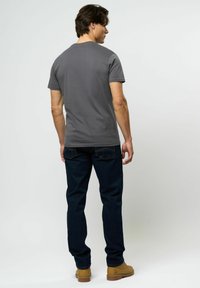 Grå bomulls t-skjorte med korte ermer, flat halslinje, sammen med mørk denim jeans og brune sko. Enkel, uformell design.