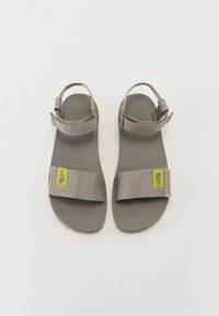 Gray sandals with a textured rubber sole, wide straps, and adjustable hardware. Features a small green logo tag on the side.