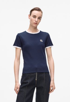Navy blue ribbed T-shirt with white collar and sleeve accents; features a small logo on the chest; fitted design and soft texture.