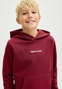Sudadera burdeos con bolsillo tipo canguro, diseñada en un tejido suave. Presenta "Originals Studio" bordado en blanco en el pecho.