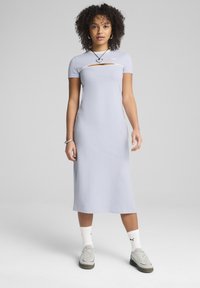 Robe midi bleu clair à manches courtes, avec un détail découpé au niveau de la poitrine. Fabriquée en tissu lisse, associée à des baskets grises et des chaussettes blanches.