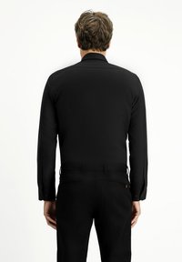 Zwarte langemouwen shirt, gladde stof met een rechte snit. Knopmanchetten en een kraaghalslijn. Gekocht met bijpassende zwarte broek.