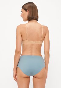Nude bh med justerbare stropper og krokfeste, kombinert med lyseblå høytalende undertøy med jevn tekstur og enkelt design.