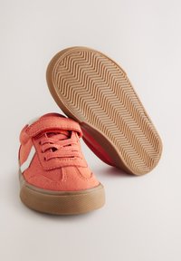 Korale filcowe trampki z gumowymi podeszwami, białymi bocznymi akcentami i wiązaniem na sznurówki. Wyposażone w wyściełany język oraz regulowany pasek na rzep.