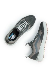 Grå och svarta träningsskor har en blandning av mocka och mesh-material, vita snörning och en gummisula med ett texturerat brunt mönster.