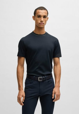 T-shirt in cotone navy con maniche corte, scollatura rotonda e cuciture a contrasto. Abbinato a pantaloni scuri e una cintura nera con fibbia in argento.