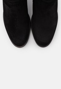 Botines de ante negro con punta redonda y tacón bajo. Textura suave y diseño minimalista sin herrajes ni acentos visibles.