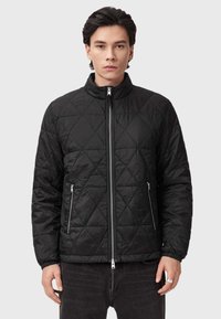 Czarna pikowana kurtka z wysokim kołnierzem, przednim zamkiem błyskawicznym i dwiema bocznymi kieszeniami. Posiada wzór w romby oraz elastyczne mankiety.