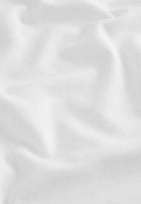 Tissu blanc avec une surface lisse et légèrement texturée, présentant des plis doux et un drapé, suggérant un matériau léger et respirant.