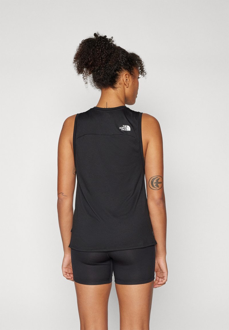 Top deportivo negro sin mangas, con un pequeño logo en la parte superior de la espalda y una textura suave. Combinado con pantalones cortos negros.